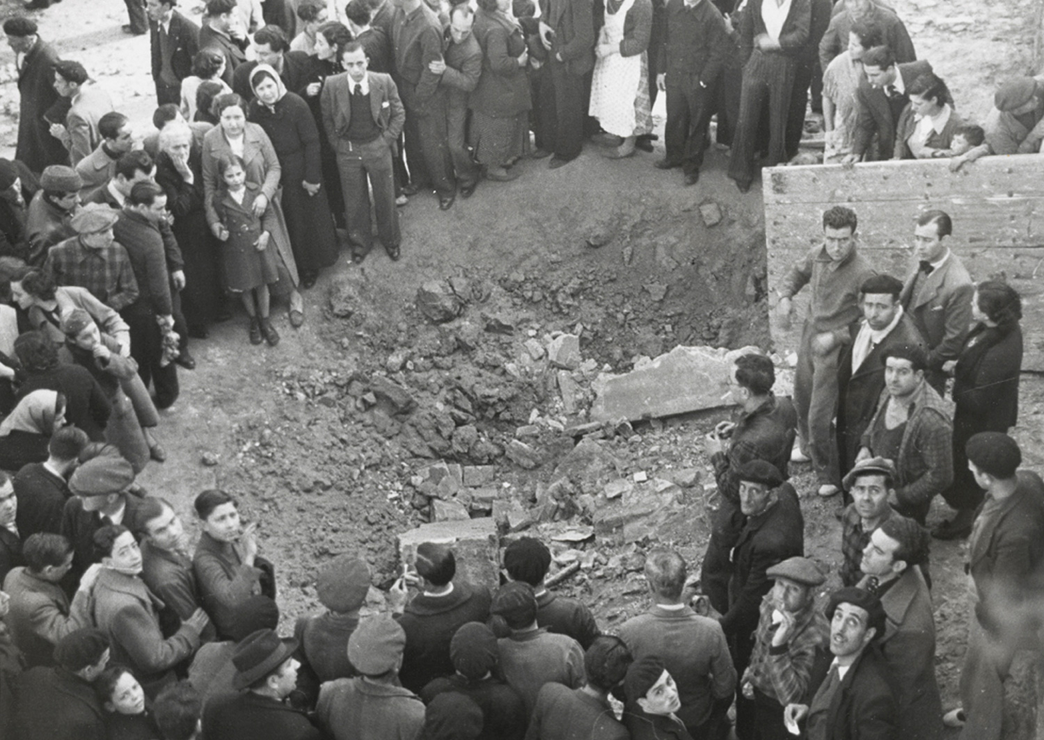 1937 AFB Bombardeig al Poble-sec. Grup de gent observant el forat que ha deixat una bomba. Autor Pérez de Rozas