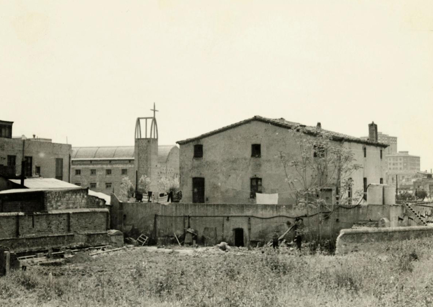 1965 AMDS Vista, des del carrer del Torrent del Perales, del solar situat davant la masia de can Mantega. Al fons, façana lateral i campanar de la parròquia de Sant Joan Maria Vianney.